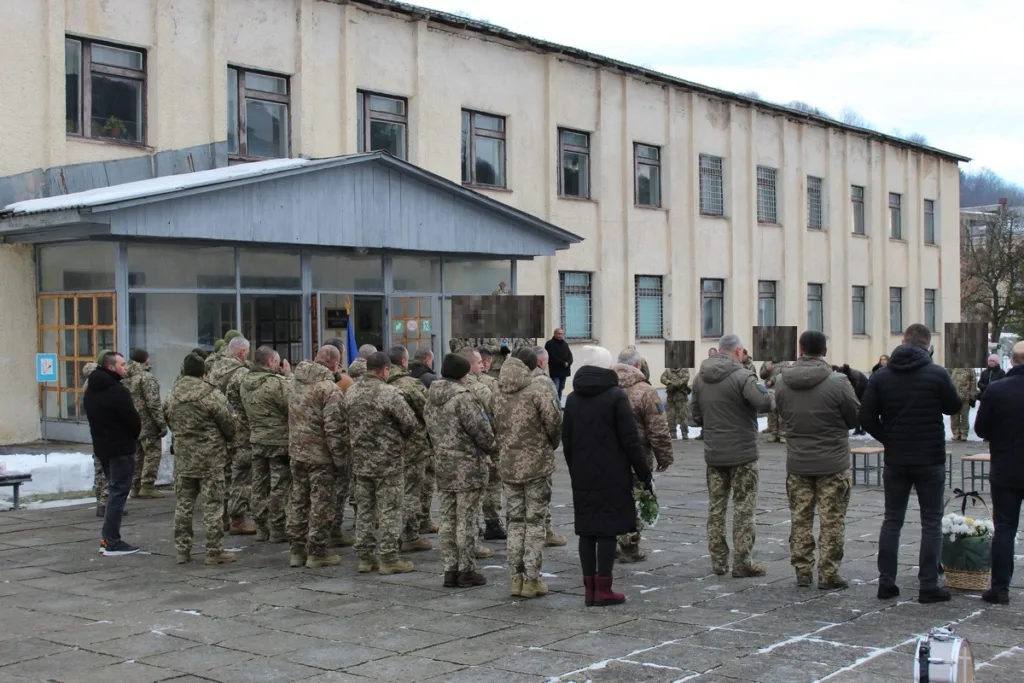 Військові та цивільні стоять перед будівлею