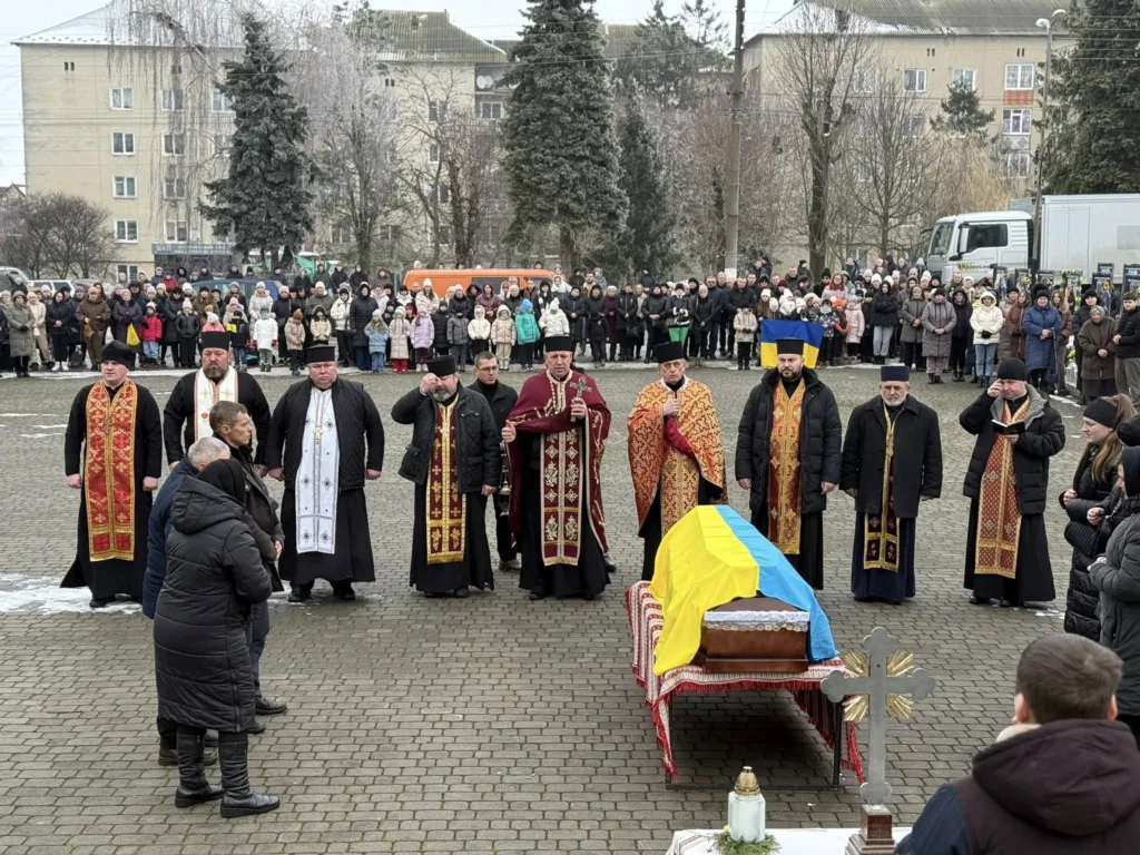 Похоронна церемонія з українським прапором та священниками