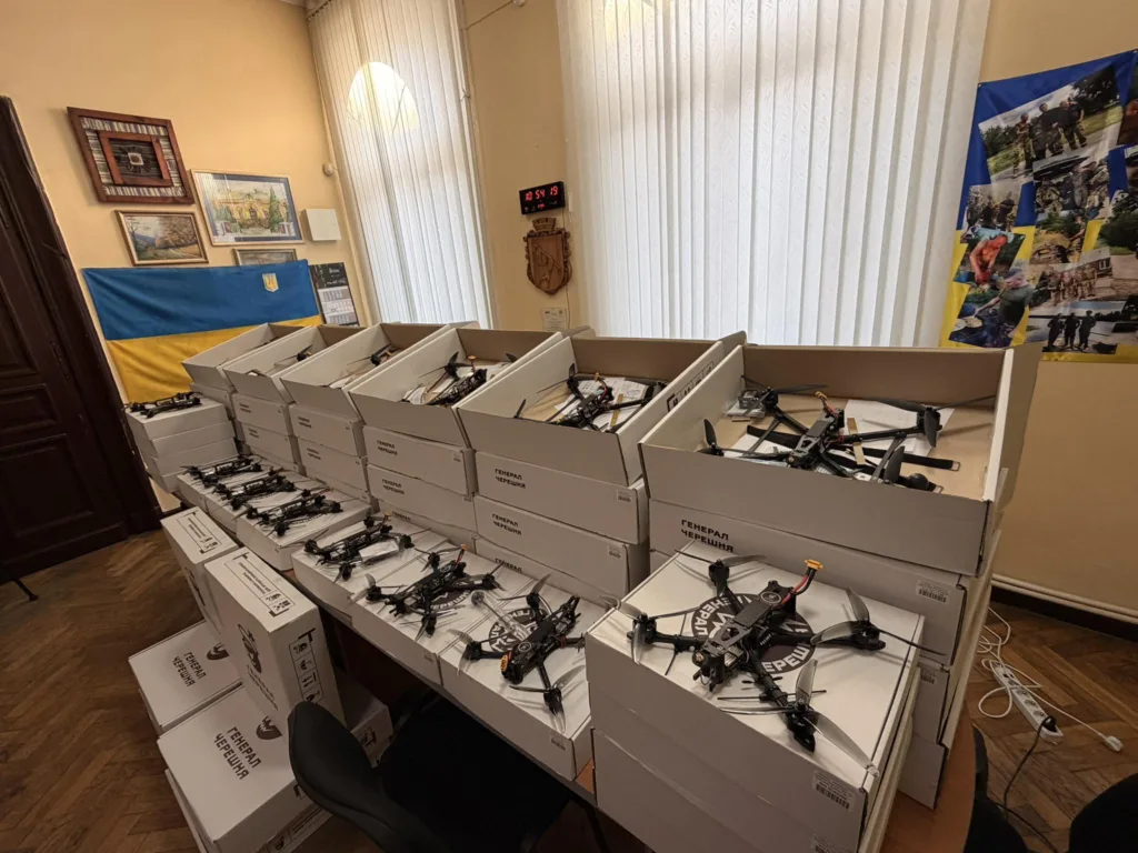 Коробки з дронами у кімнаті з прапором України