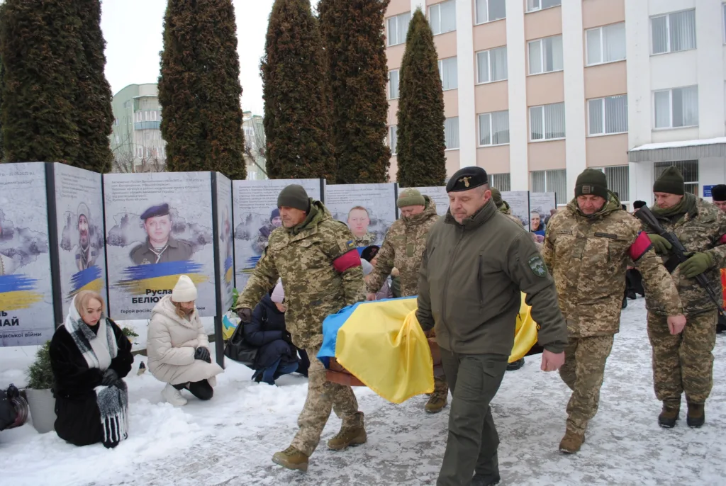 Військові несуть труну, накриту прапором України