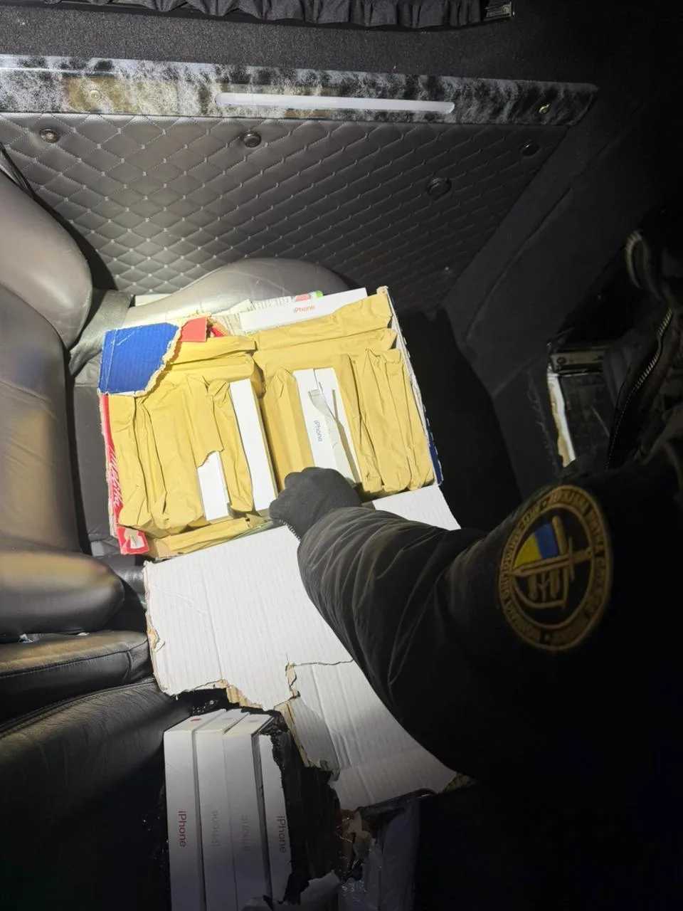 Правоохоронець перевіряє коробки з айфонами в авто