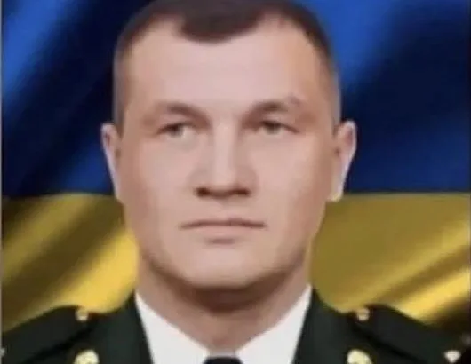 Військовий у формі на тлі прапора України