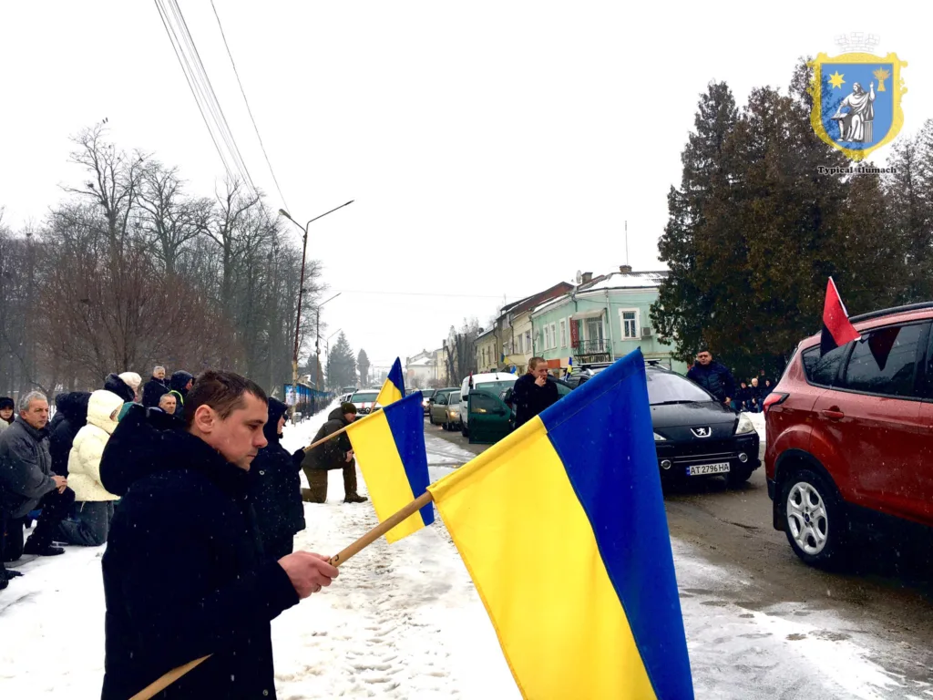 Люди з українськими прапорами на зимовій вулиці