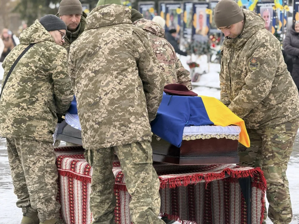 Військові несуть труну, накриту українським прапором