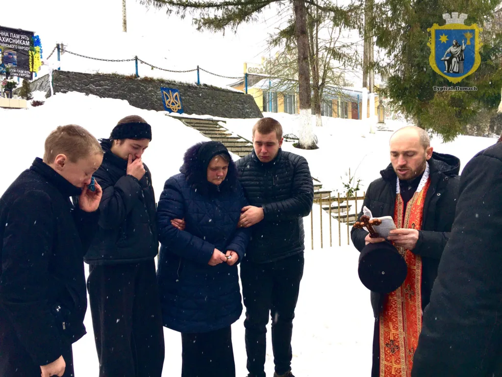 Священник проводить поминальну молитву взимку