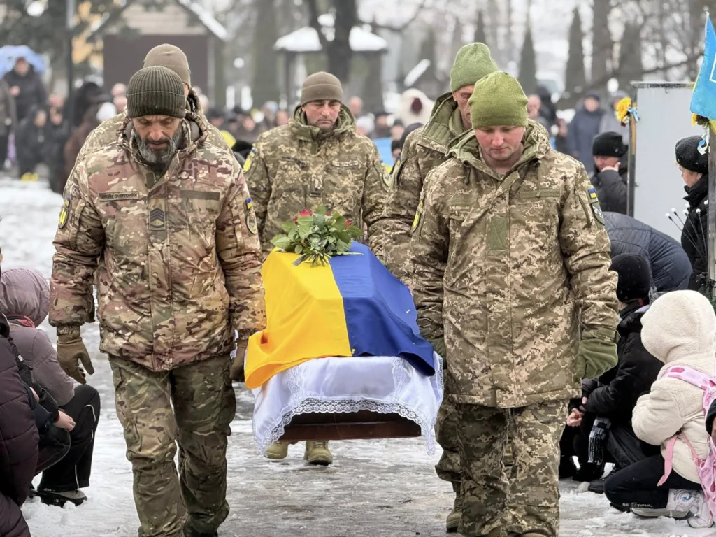 Військові несуть труну, вкриту українським прапором