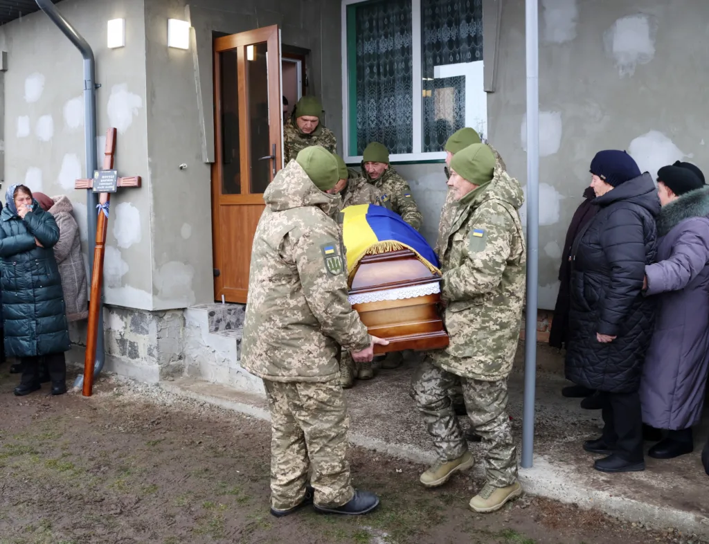 Військові несуть труну, покриту українським прапором