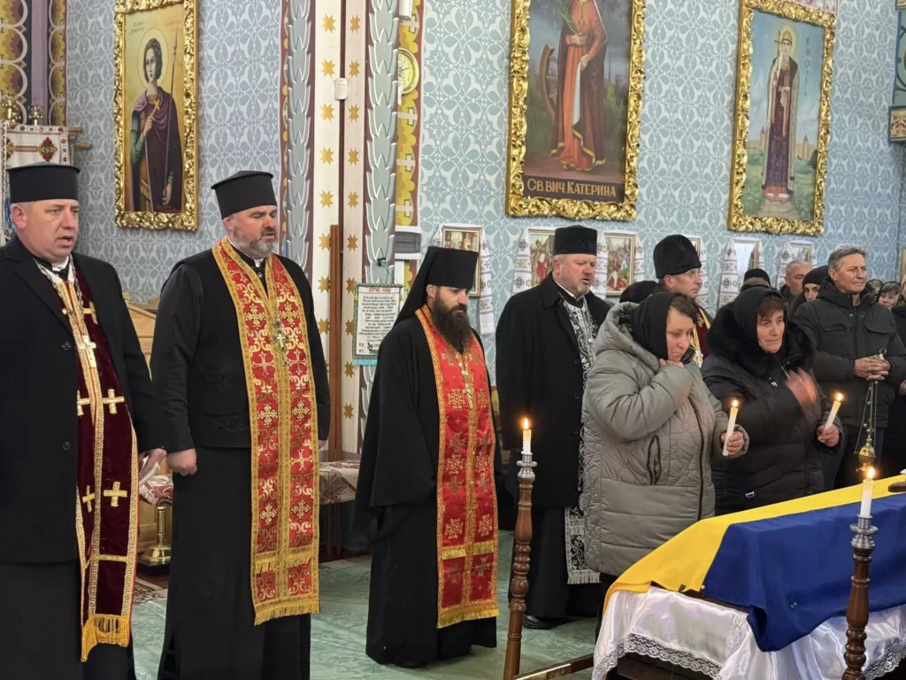 Священники і люди моляться біля труни в церкві