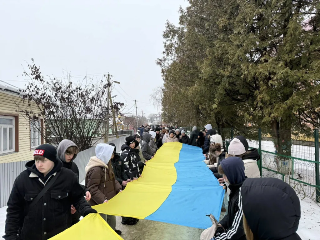 Люди тримають великий український прапор на вулиці