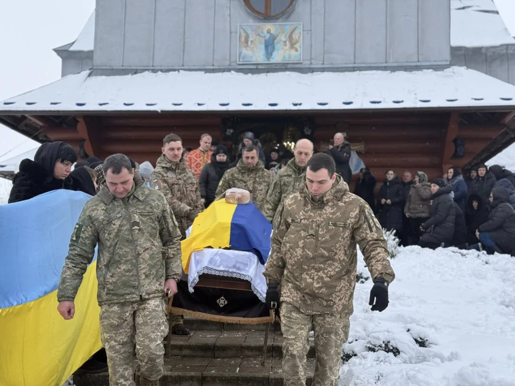 Військові несуть труну, накриту українським прапором