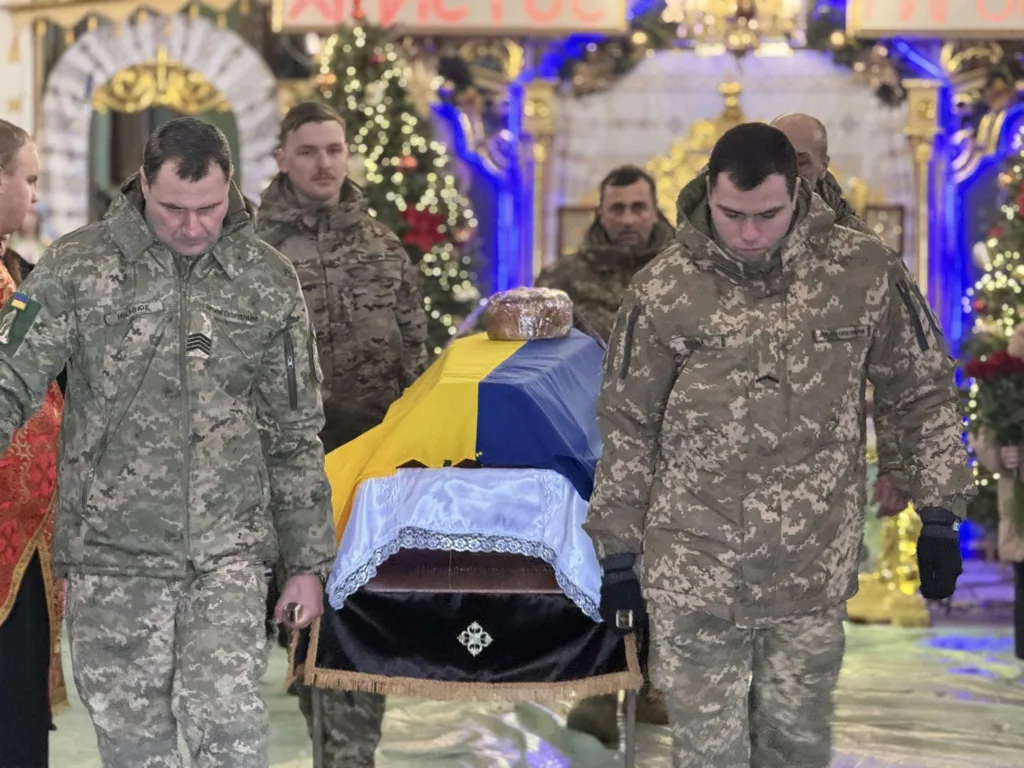 Військові несуть труну, накриту прапором України