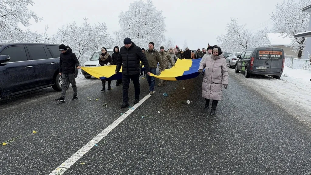 Люди несуть великий прапор України взимку