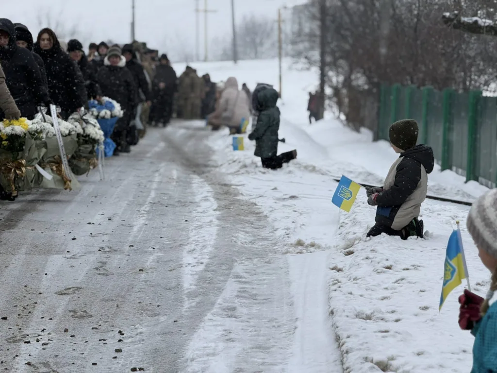 Люди на колінах з прапорами України взимку