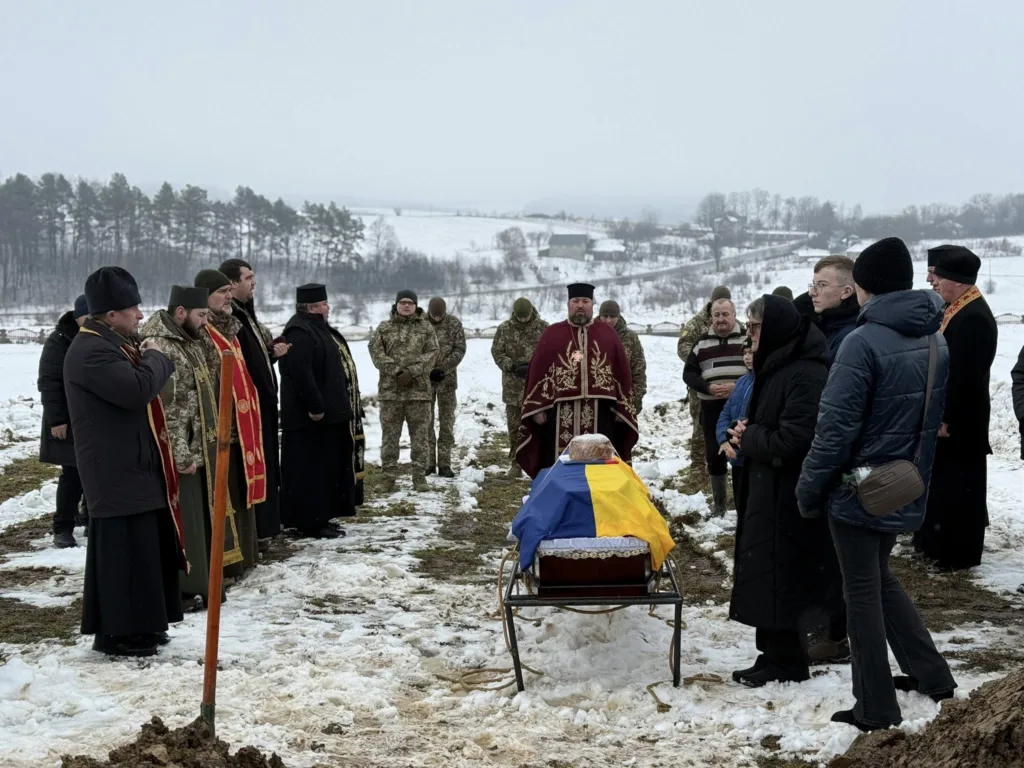 Поховання військового на снігу під українським прапором