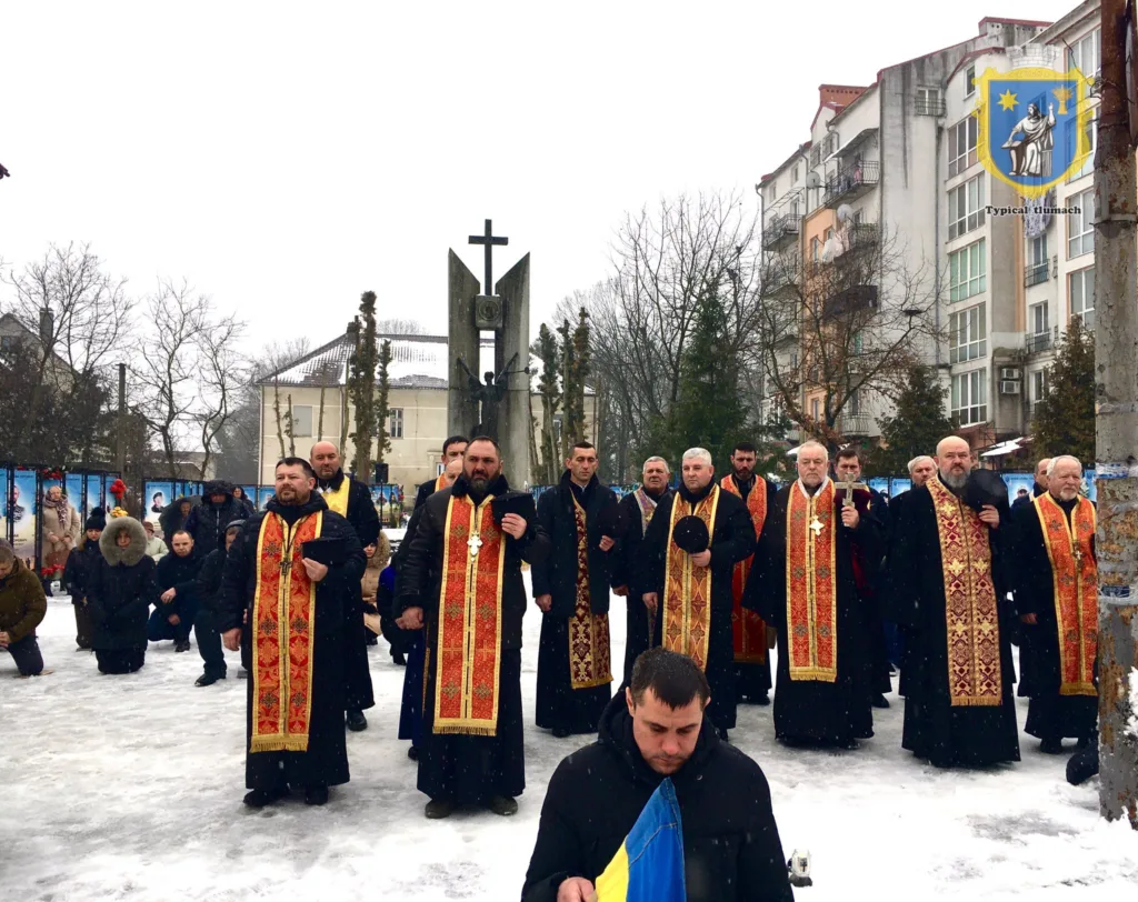 Священики моляться біля пам’ятника взимку