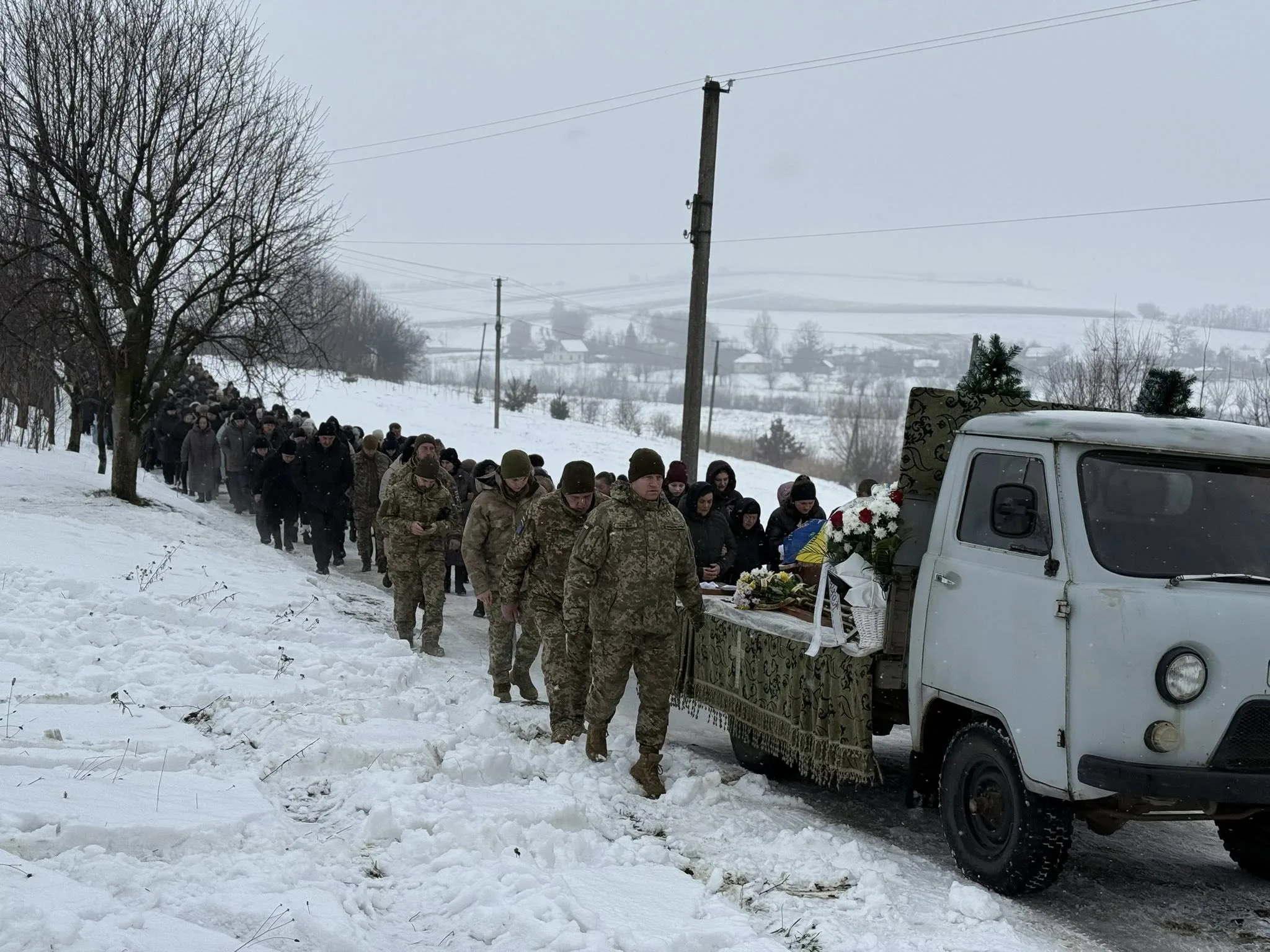 Похоронна процесія військових у засніженому селі