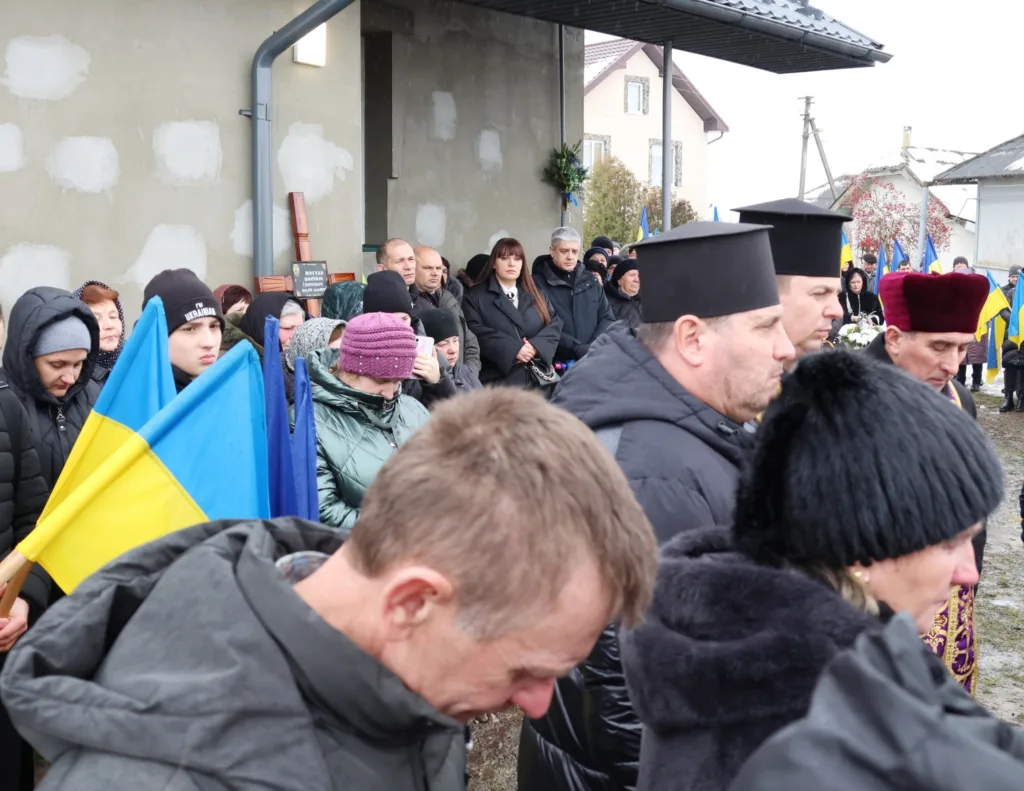 Люди з українськими прапорами на траурній церемонії