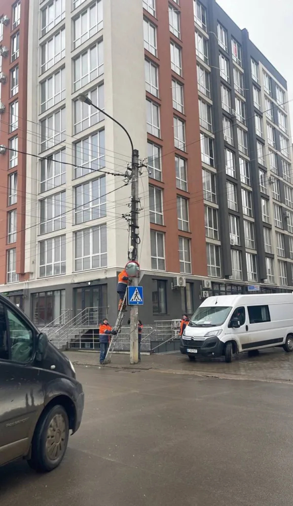 Робітники ремонтують ліхтар біля житлового будинку