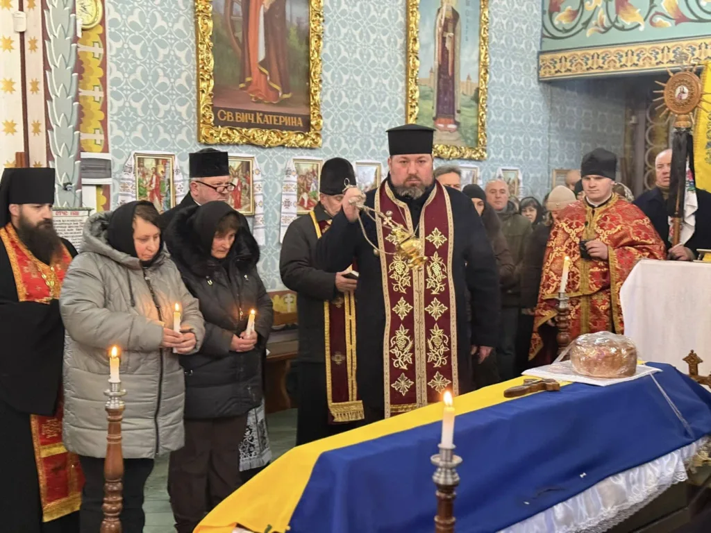 Священники і люди моляться біля труни в церкві