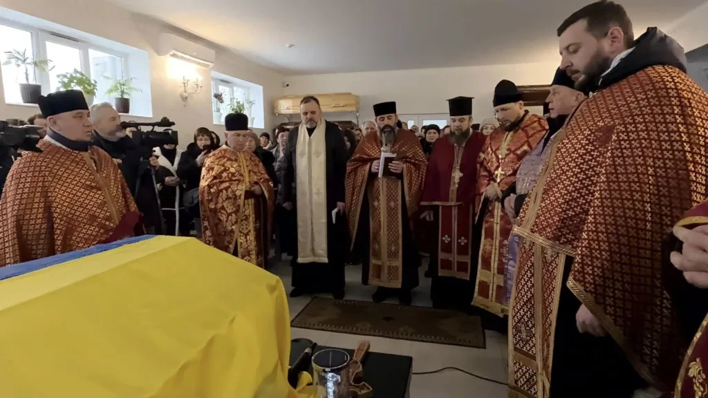 Священники проводять похоронну церемонію біля труни
