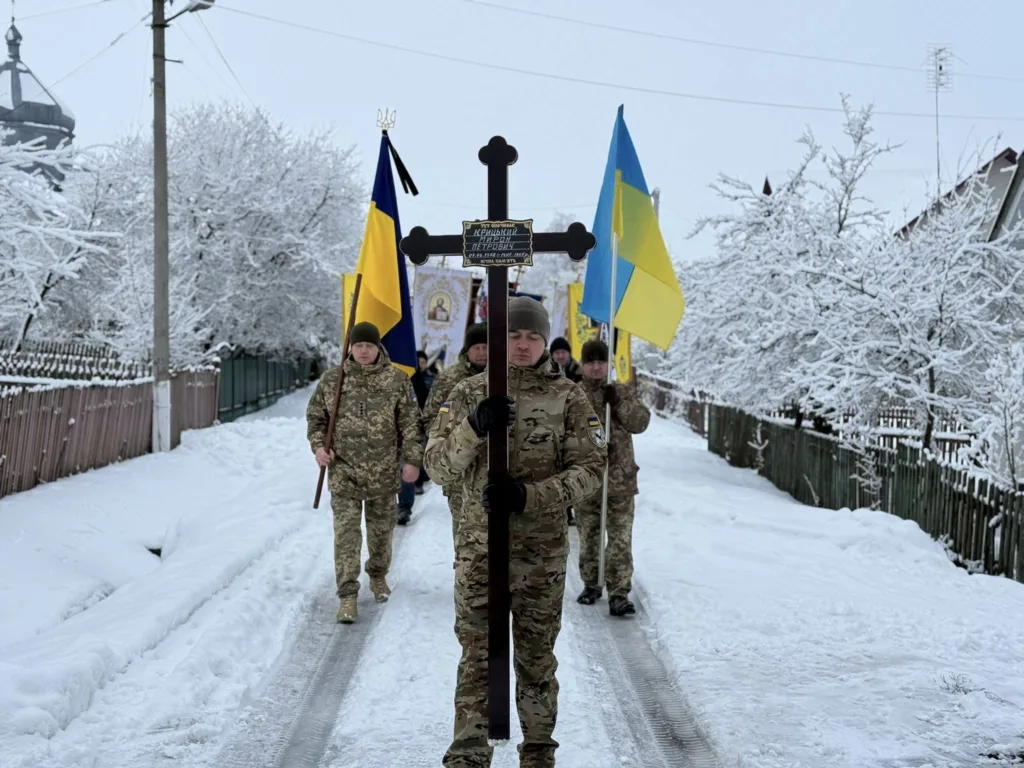 Військові з прапорами України йдуть сніжною вулицею