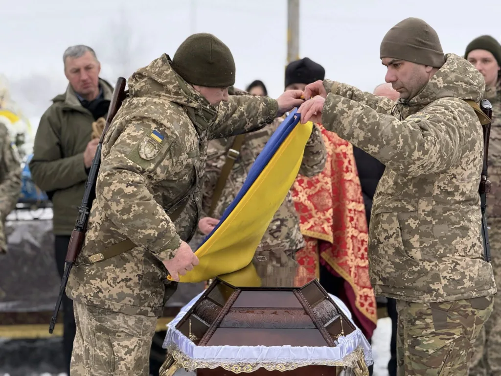 Військові накривають труну українським прапором
