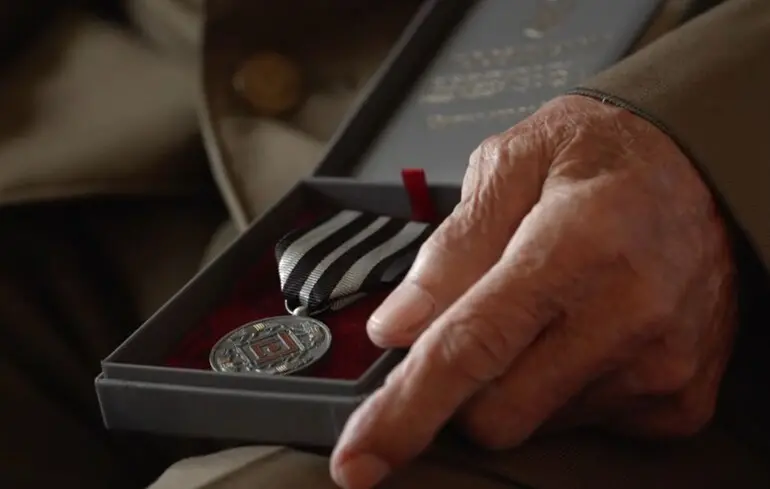 Рука ветерана тримає медаль у футлярі