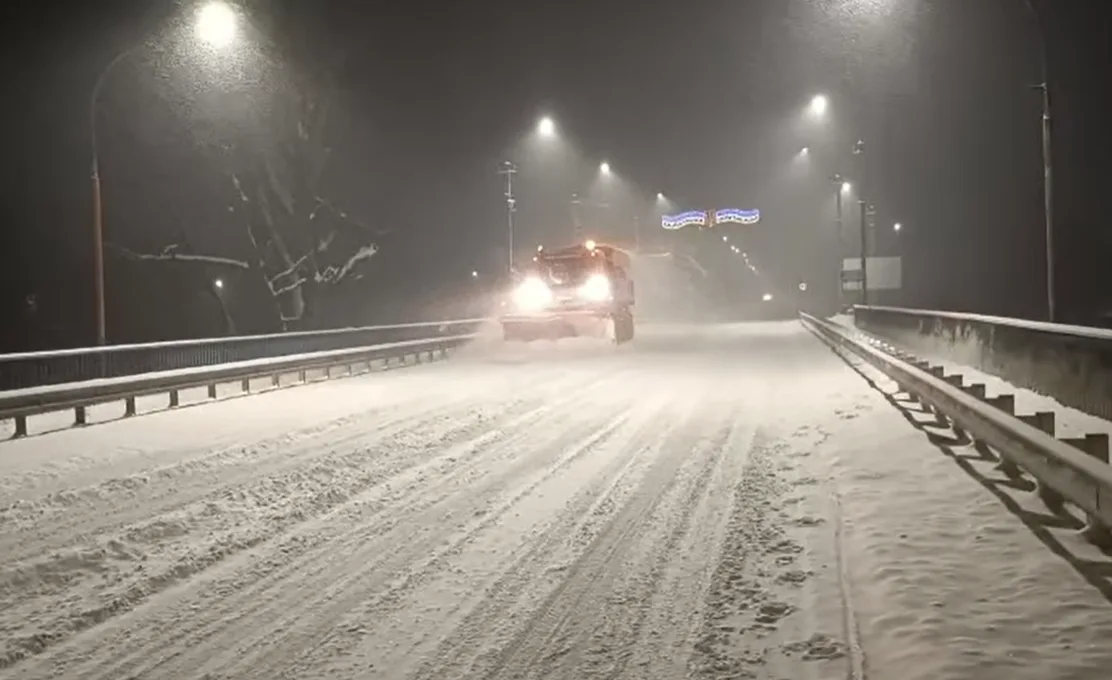 Снігоприбиральна машина чистить засніжену дорогу вночі