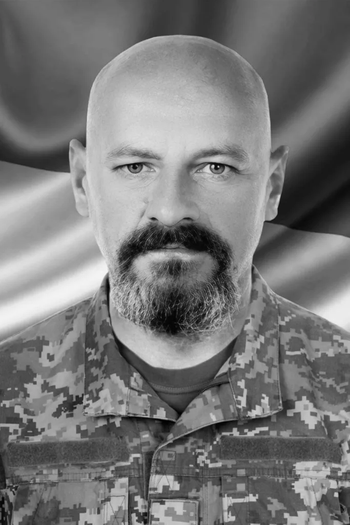 Український військовий у камуфляжі на фоні прапора