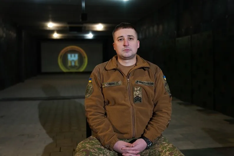 Військовий сидить у камуфляжі в темному приміщенні