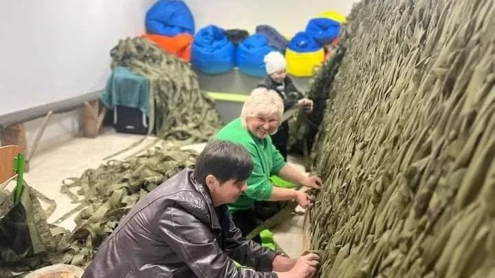 Люди плетуть маскувальну сітку в приміщенні