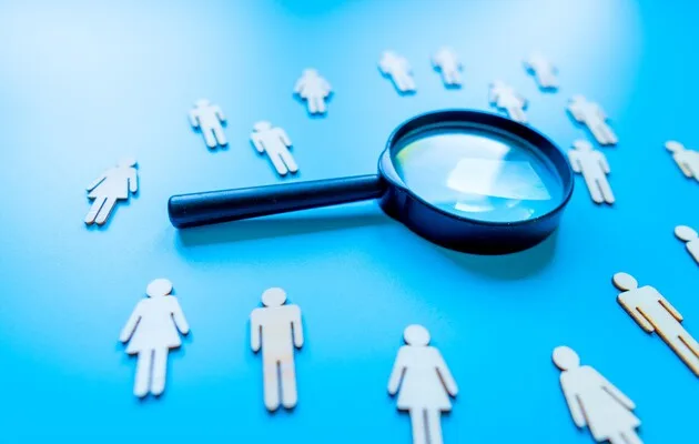 Лупа над фігурками людей на синьому фоні