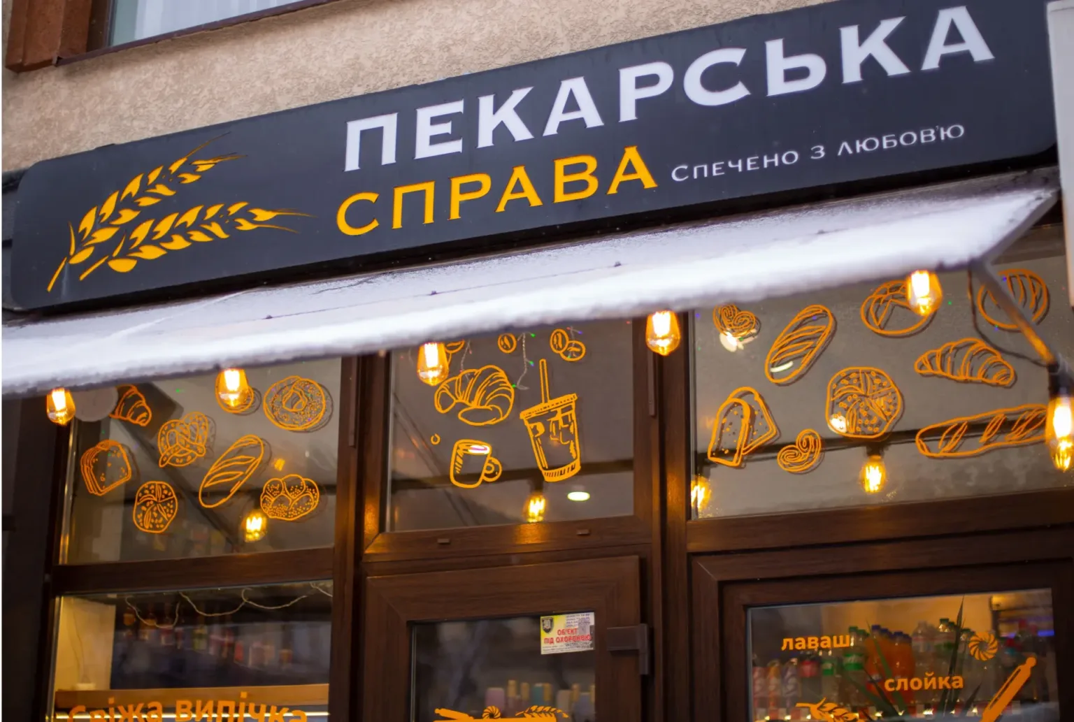 Вивіска пекарні з жовтими малюнками випічки