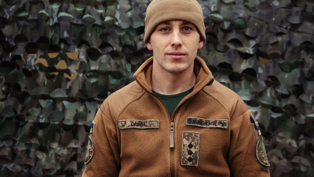 Український військовий у камуфляжі перед сіткою