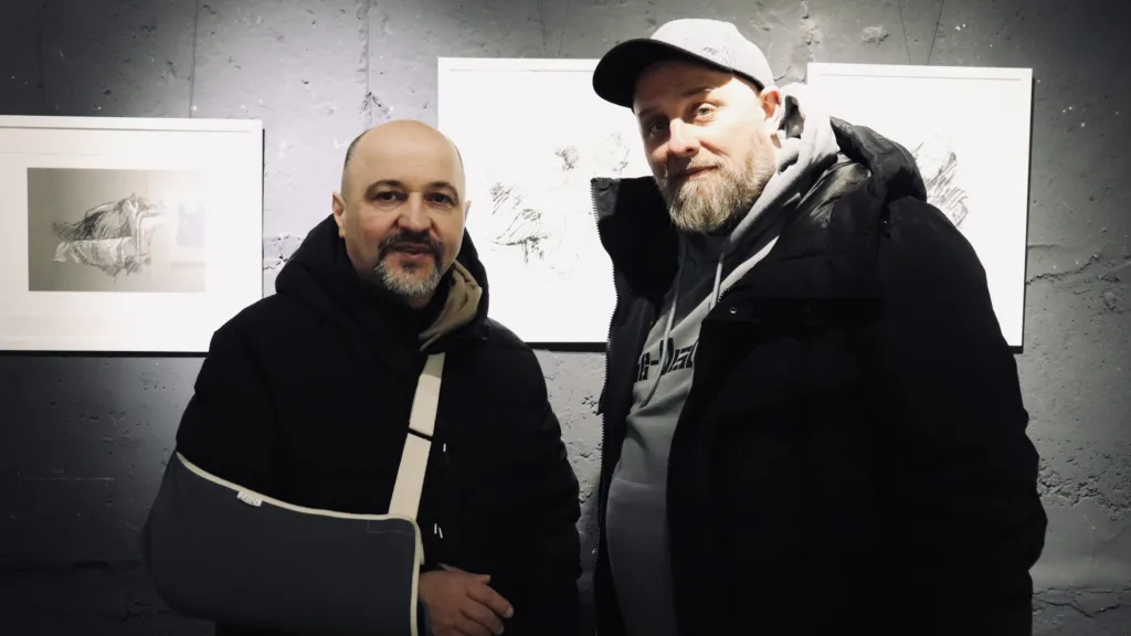 Двоє чоловіків біля картин у галереї