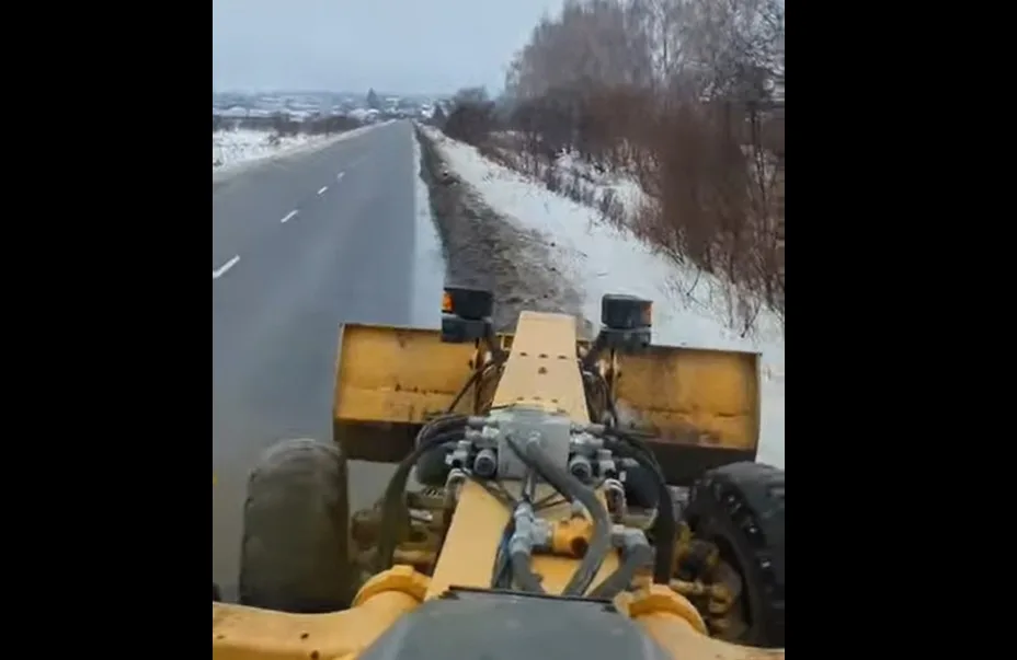 Бульдозер очищає узбіччя засніженої дороги