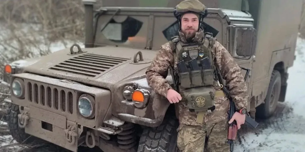 Український військовий біля броньованого автомобіля взимку