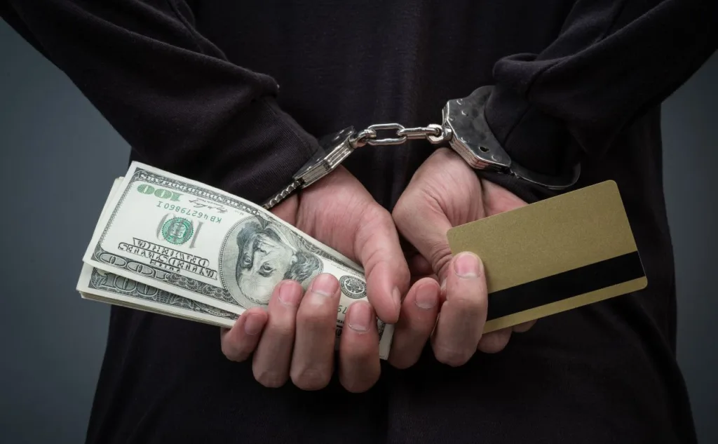 Руки в кайданках з грошима та карткою
