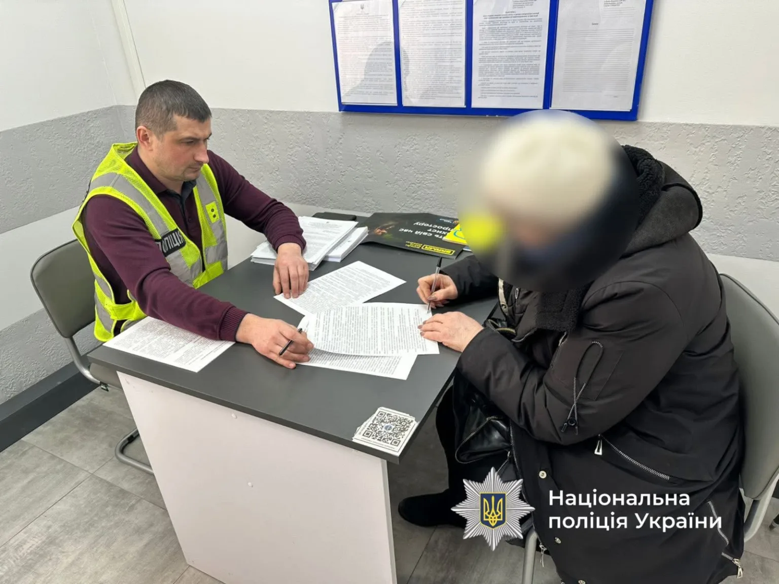 Поліцейський допомагає жінці заповнити документи