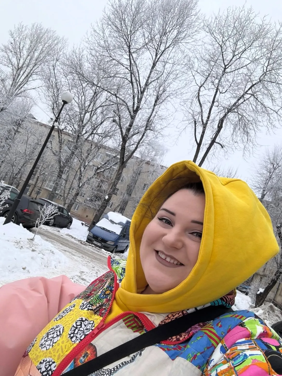 Жінка усміхається на зимовій вулиці з снігом