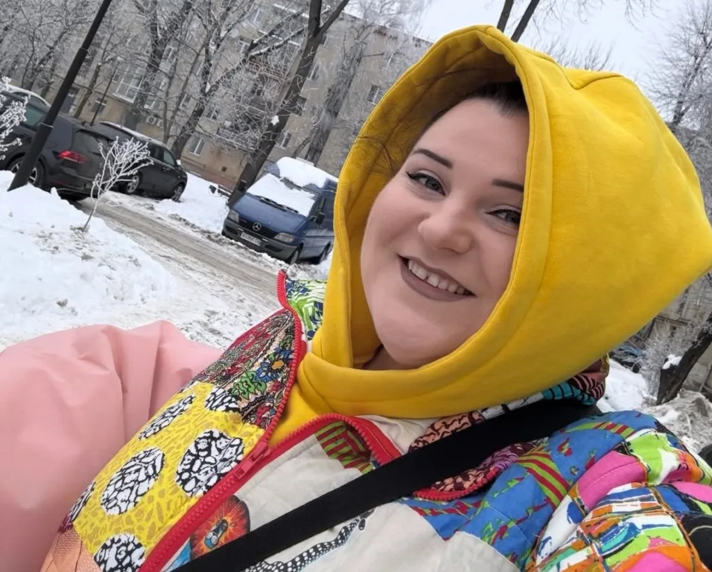 Усміхнена людина на снігу в яскравій куртці