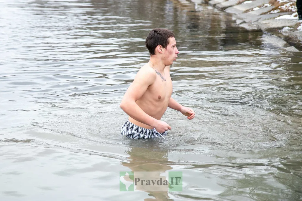 Чоловік купається в холодній річці взимку