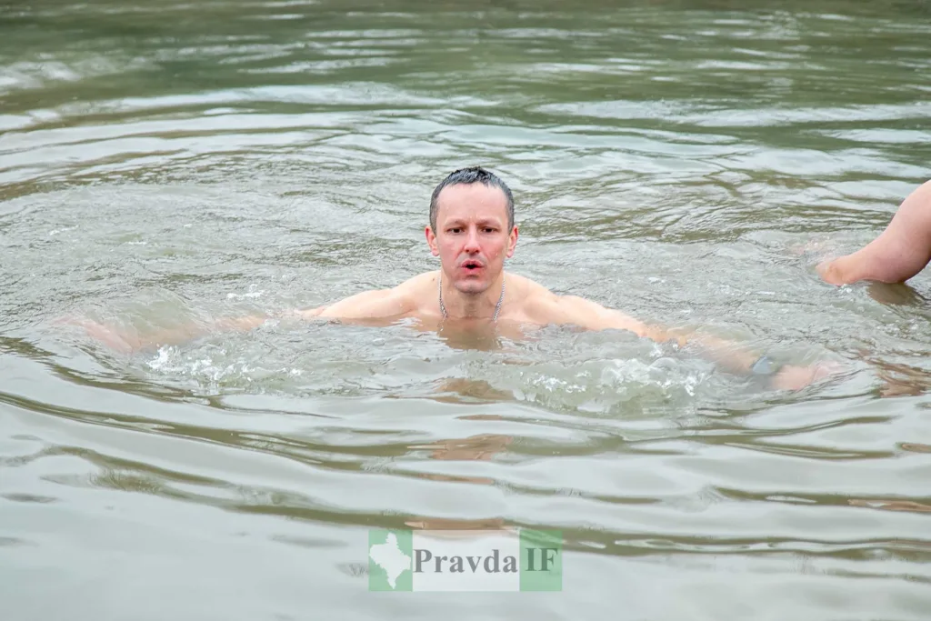 Чоловік купається в холодній річці взимку