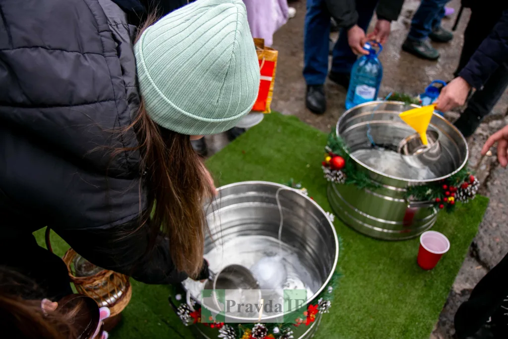 Люди набирають воду зі святкових металевих відер