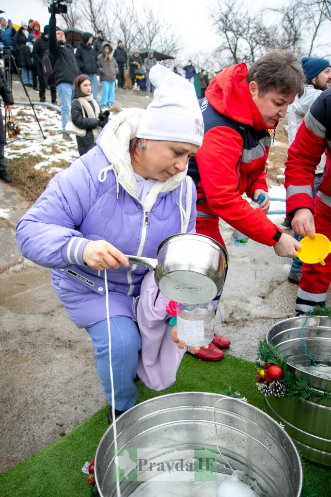 Жінка набирає освячену воду взимку на вулиці