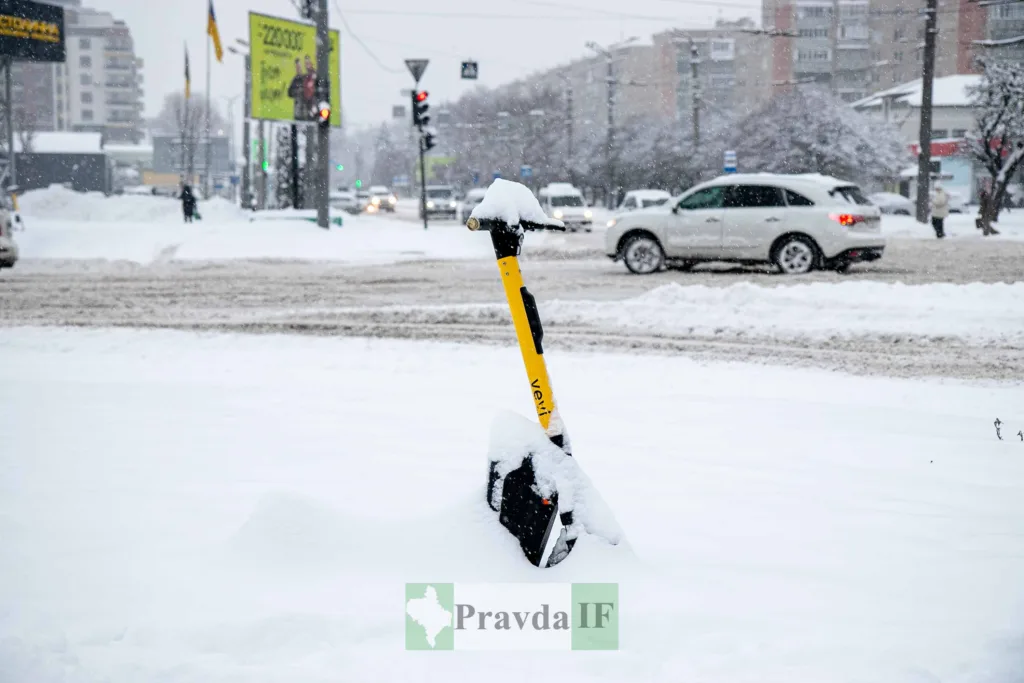 Електросамокат засипаний снігом на зимовій вулиці
