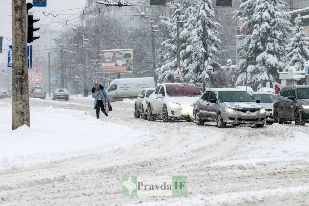 Засніжене міське перехрестя з автомобілями та пішоходом