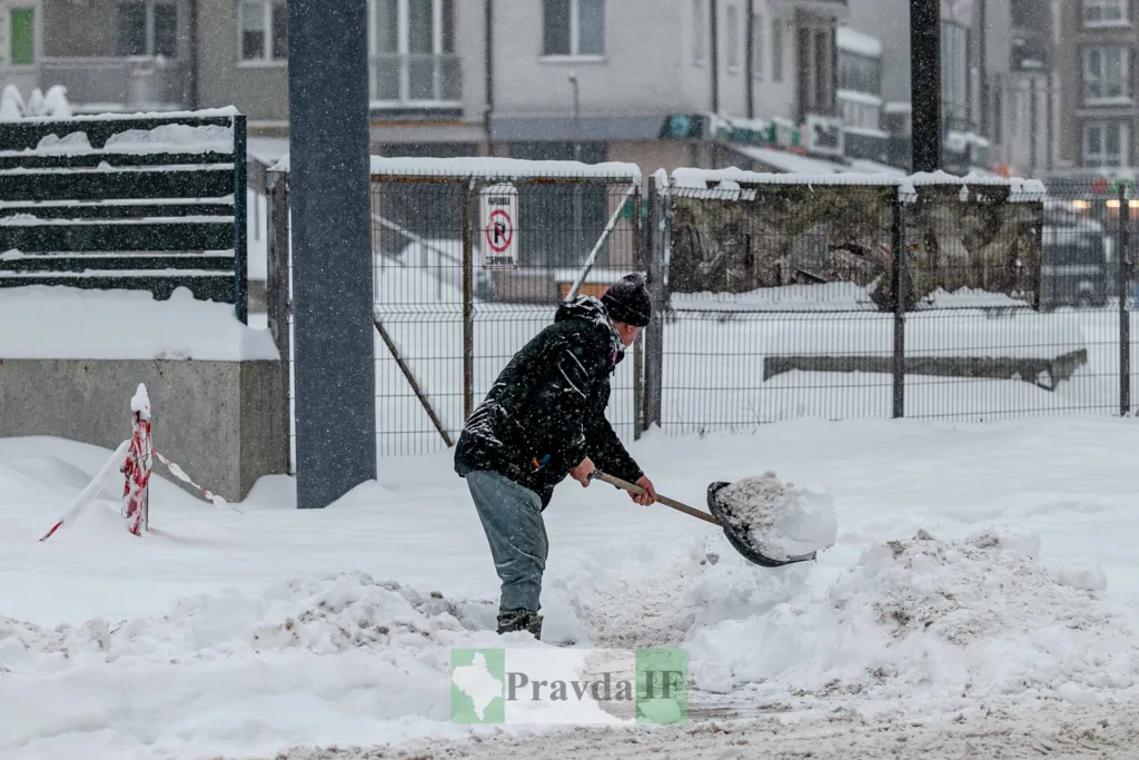 Людина розчищає сніг лопатою на вулиці