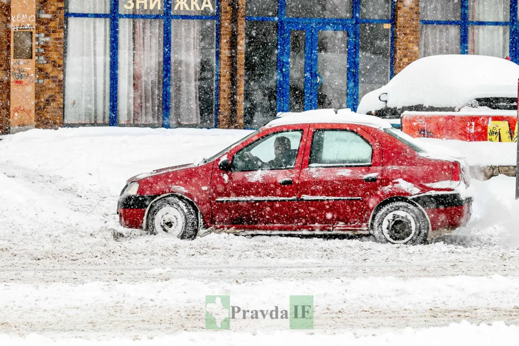Червоний автомобіль їде засніженою дорогою