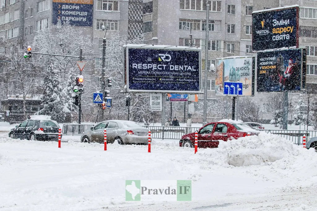 Міська вулиця взимку, автомобілі та снігопад